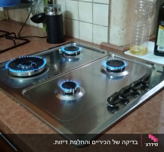 כיריים גז עם ארבעה מבערים דולקים במטבח